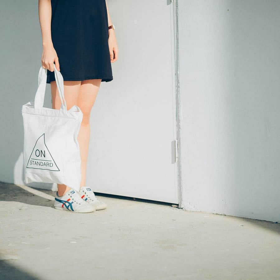 A woman holding a bag beside a wall