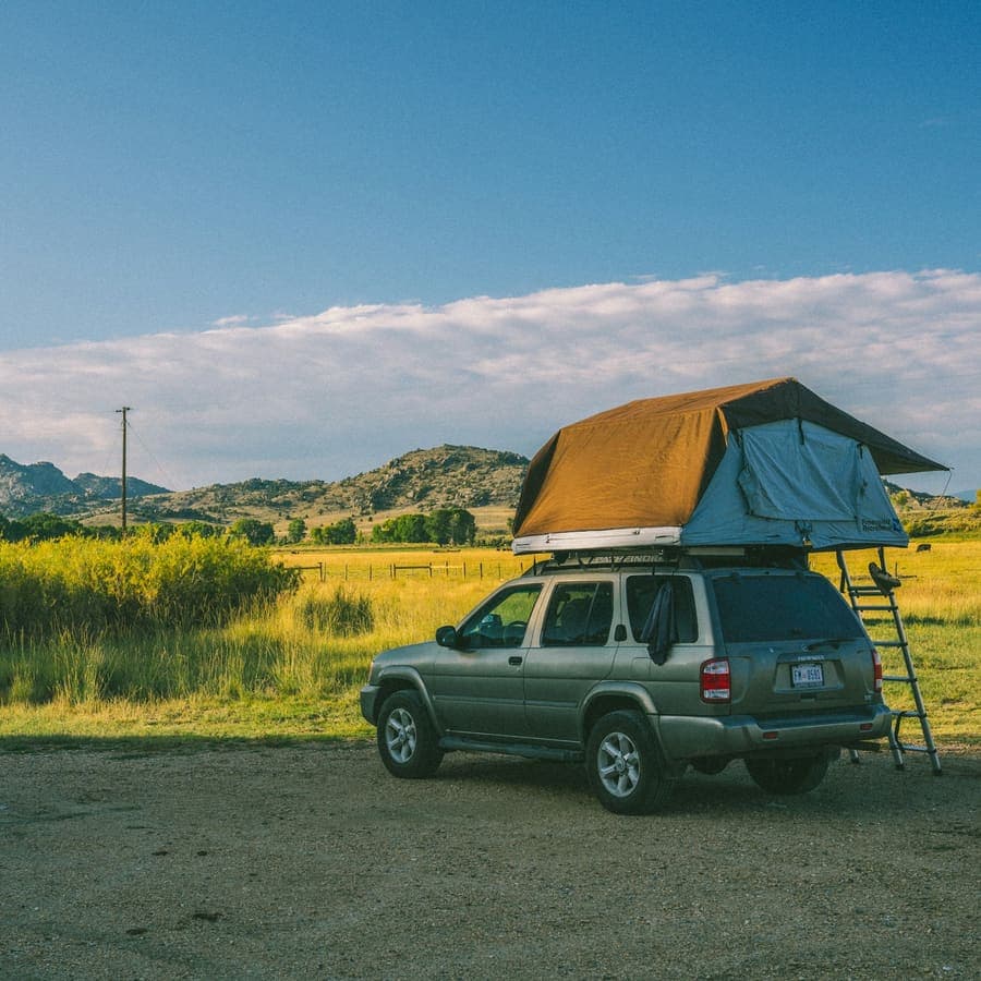 A rooftop tent open on a truck in a field