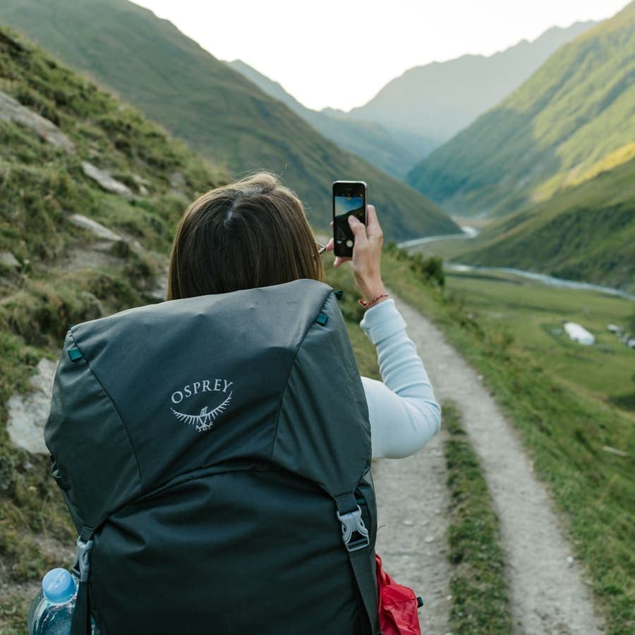 A woman walking a dirt road between mountains