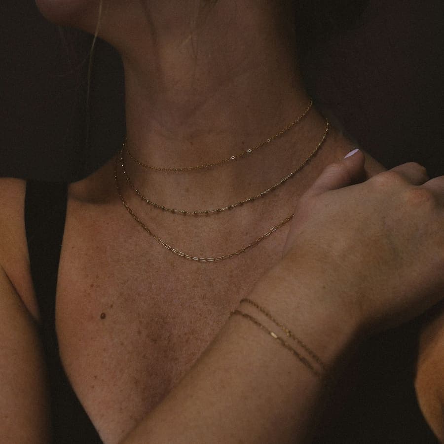 Fine gold chains layered at the collarbone