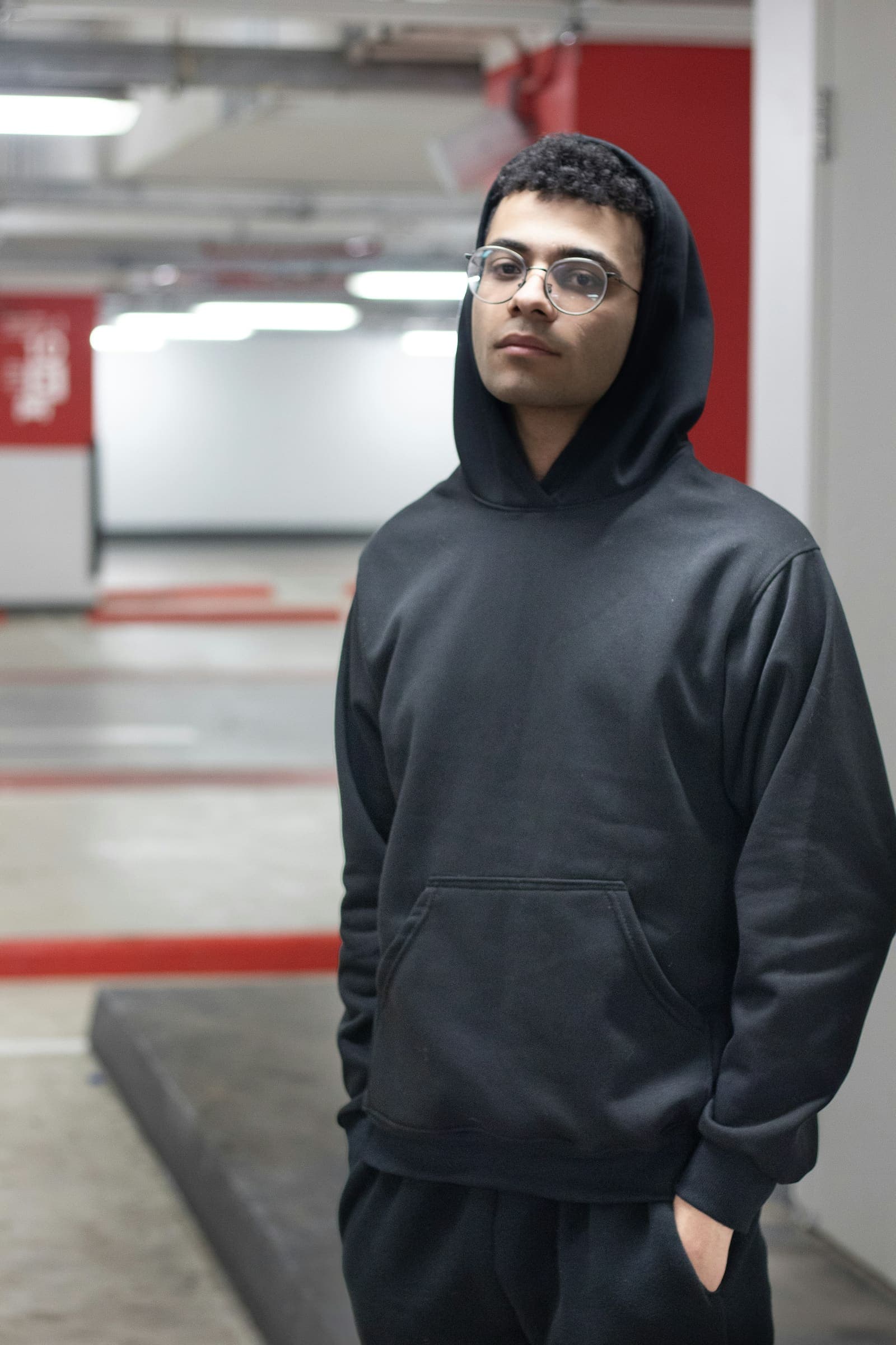 A man in a black hoodie in an underground car park