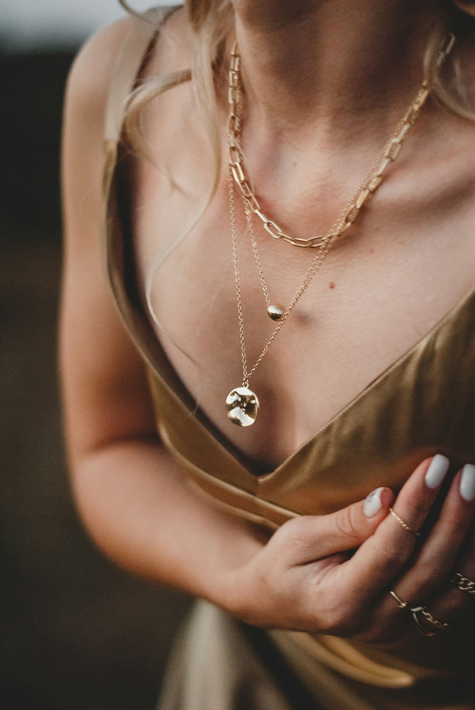 A woman in a gold dress wearing a gold necklace
