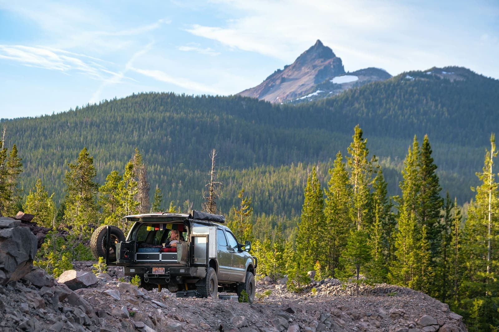 A truck with a rooftop tent below a mountain