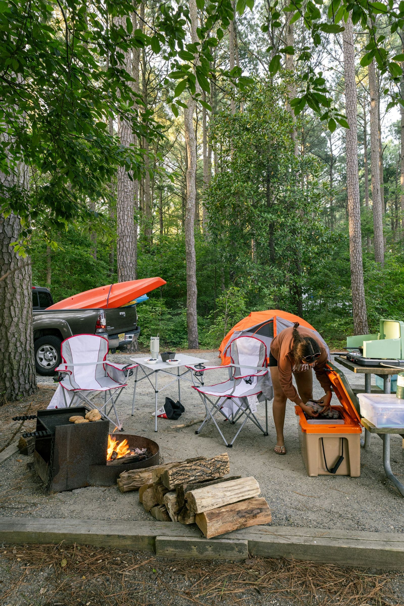 A campfire under an awning at night, the truck behind