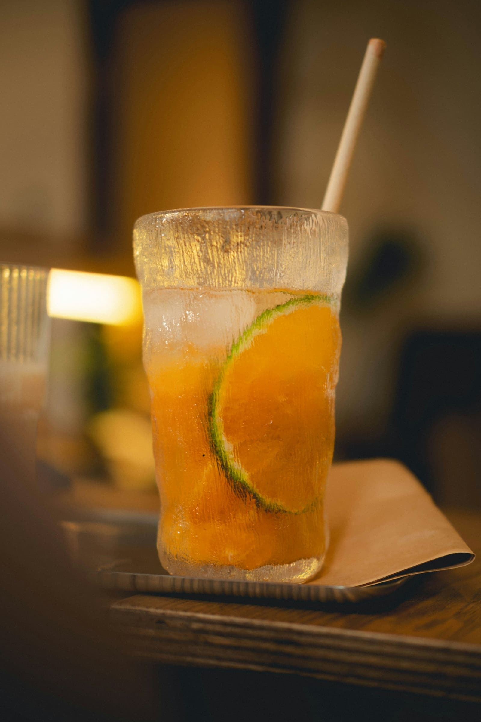 A sparkling orange drink with ice and a straw